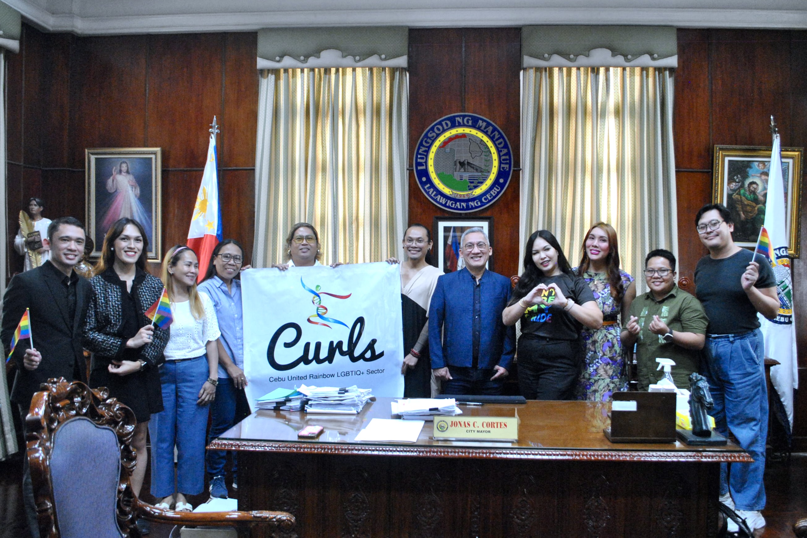 People stand behind an office desk with a CURLS sign.