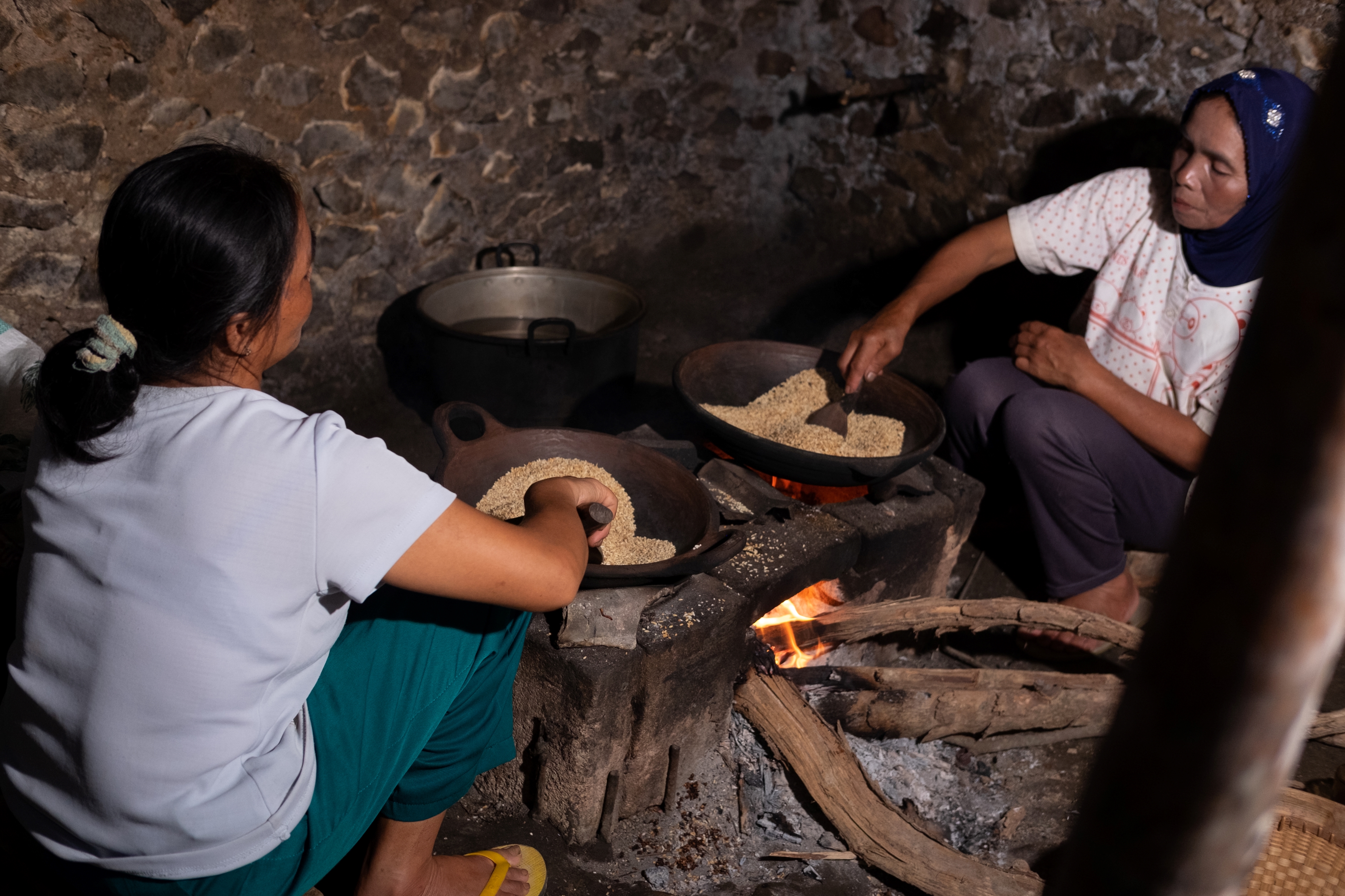 Two women cooking in a traditional wooden stove