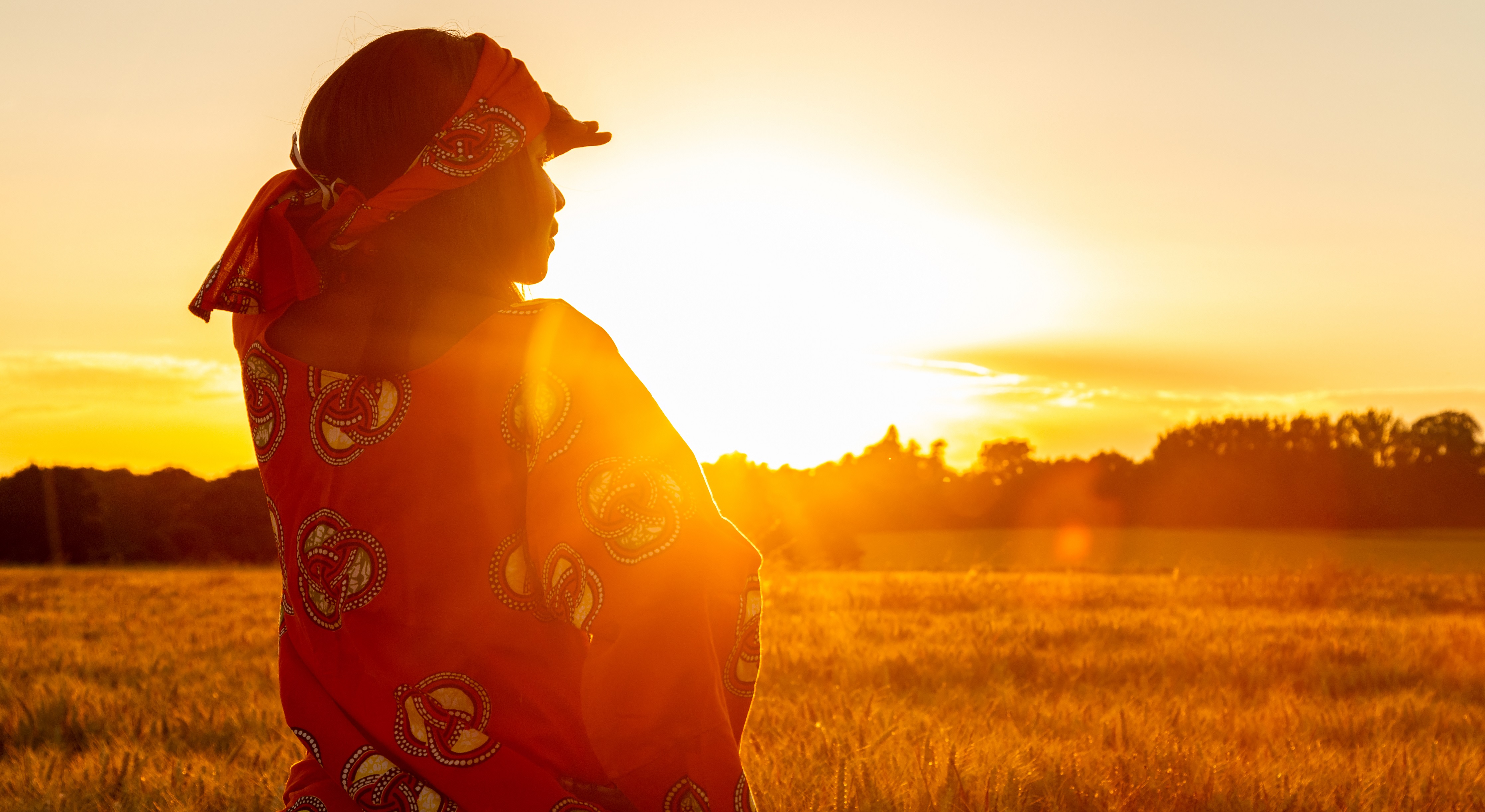 Woman gazing at landscape with an orange sunset in the background