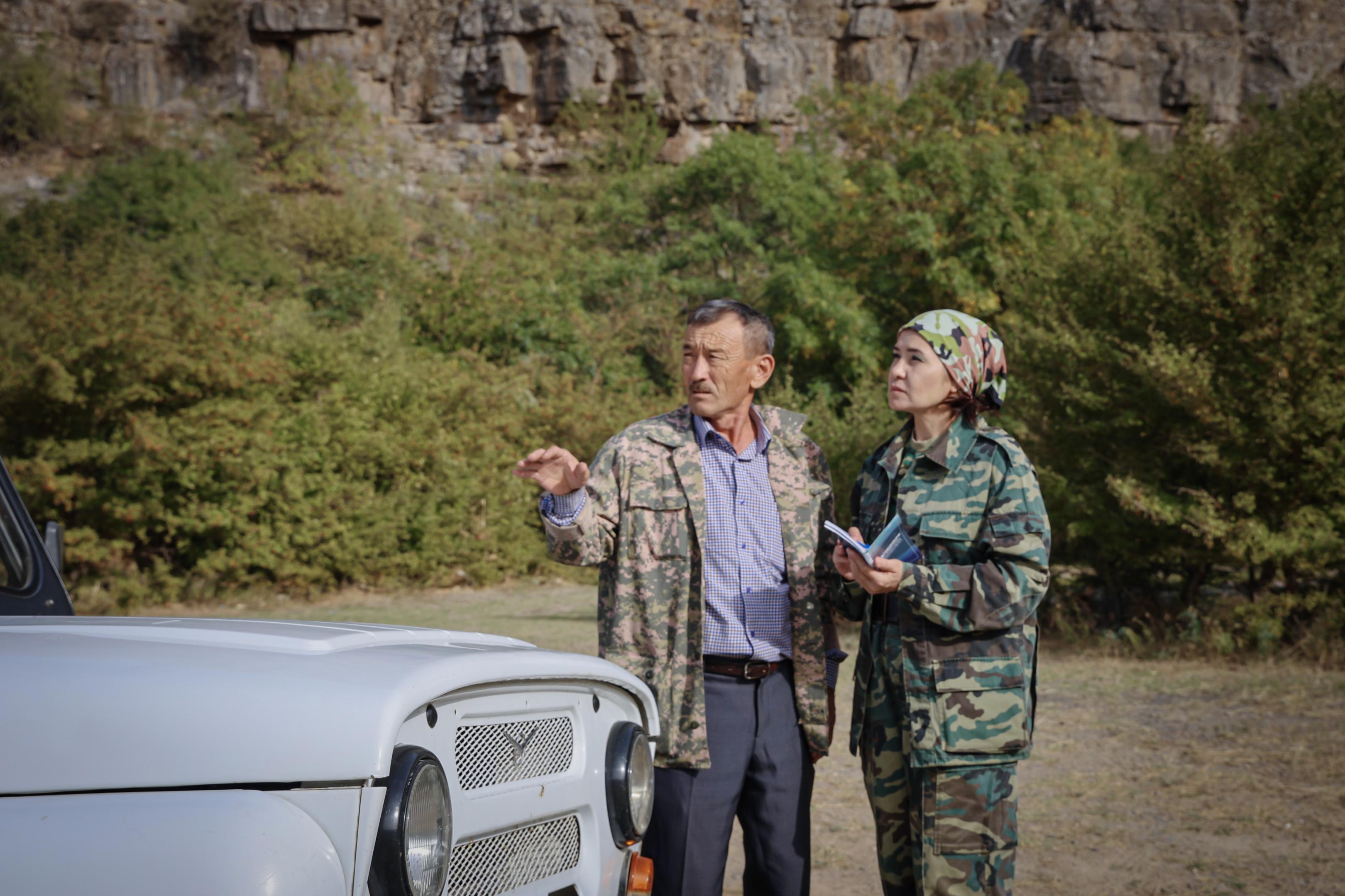 a man and woman standing in front of a car