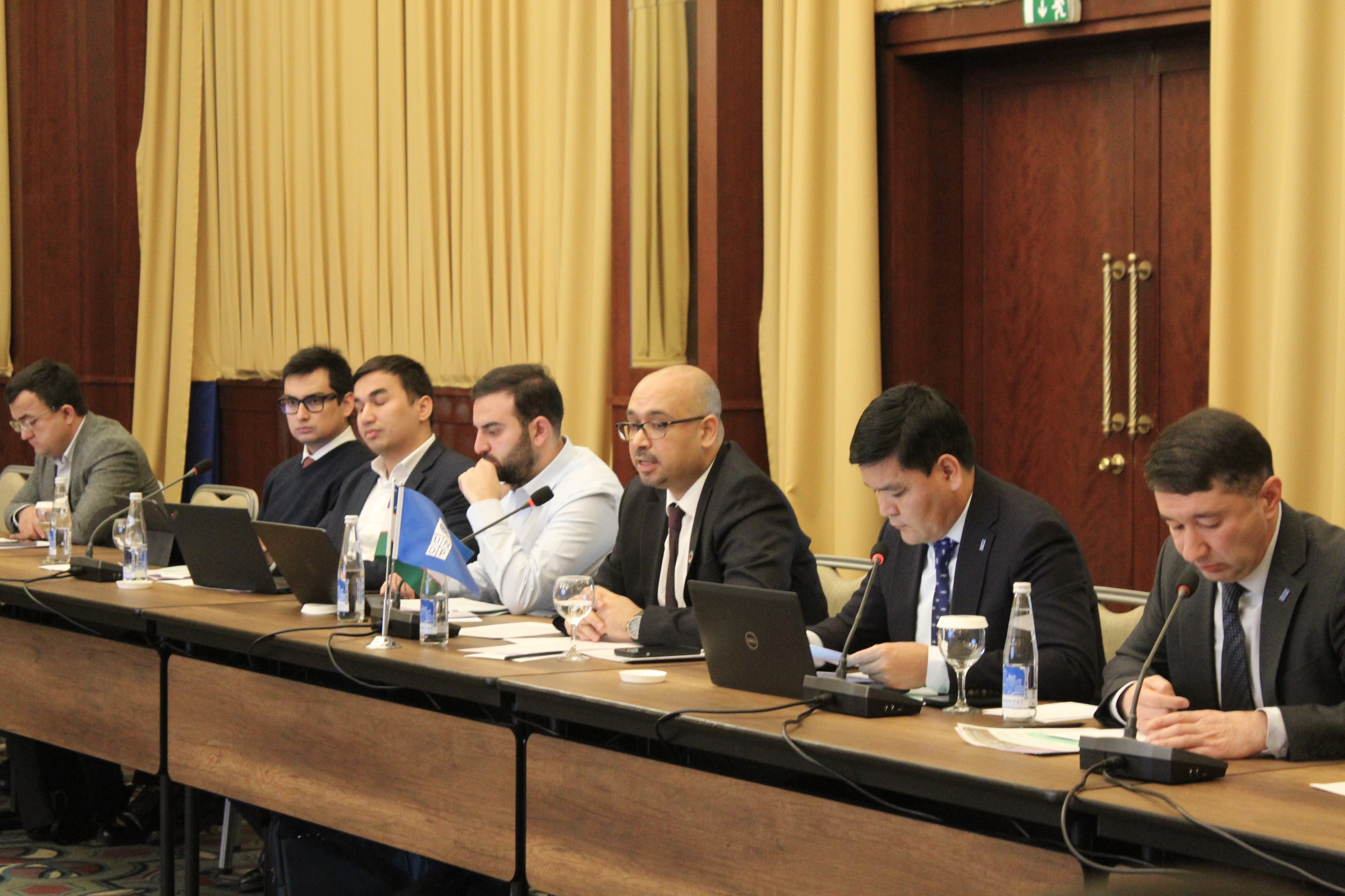 a group of people sitting at a desk in front of a curtain