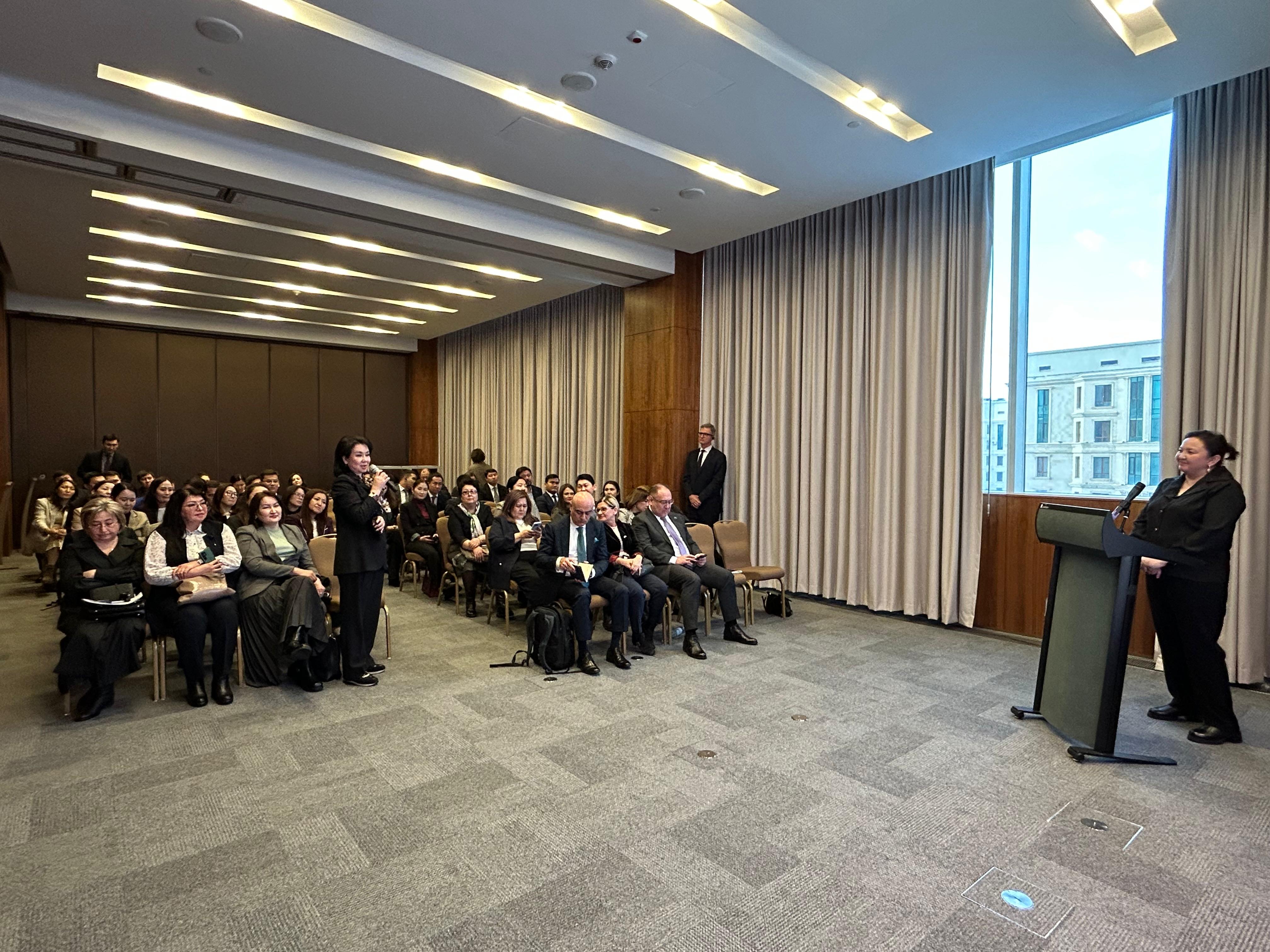 a group of people listening to a female speaker 