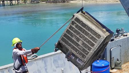 Industrial grade air conditioning unit just pulled out the sea off shore Green Turtle Cay in Abaco, The Bahamas is being transferred onto a barge.
