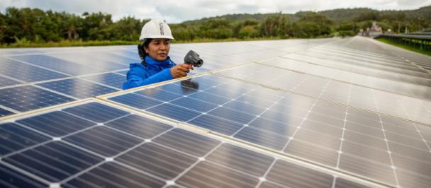 Woman in hard hat works on solar panels