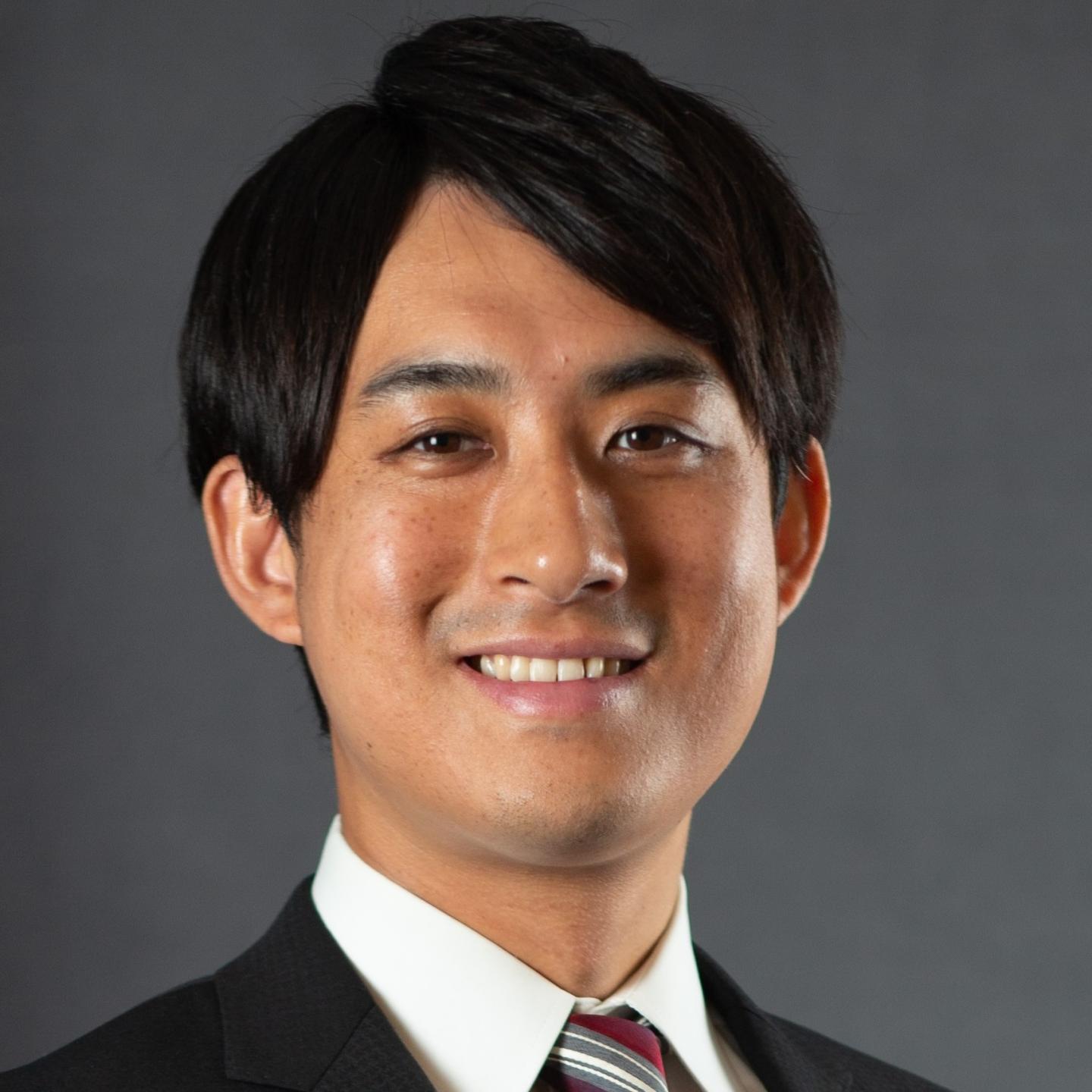 a man wearing a suit and tie smiling and looking at the camera